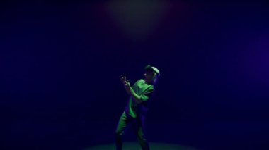 Excited player enjoying vr game in neon lights room. Futuristic man playing using headset controllers in augmented reality. Unrecognized gamer exploring metaverse simulation. Trendy innovation concept