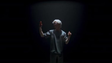 Cyber man experiencing virtual reality in dark room. Futuristic guy swiping air gesturing in studio light. Focused blonde gamer touching invisible panel in metaverse. Player immerse explore simulation