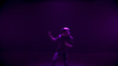 Cyber man playing vr game in neon lights. Excited gamer enjoying augmented reality in headset. Unrecognized blonde guy using controllers interacting metaverse simulation. Teenager rest in cyberspace