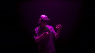 Gamer enjoying virtual reality in neon light. Focused man using console headset immersing metaverse simulation. Unrecognized guy playing checking controllers in hands. Trendy entertainment concept.