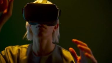 Young man touching playing virtual world game closeup. Focused gamer wearing holographic augmented reality glasses enjoying in neon light. Guy VR digital space. Metaverse 3d modern technology concept