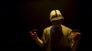 Neon gamer immersing virtual reality world in headset. Excited unknown man look controllers exploring online simulation. Blonde player enjoying metaverse technology in glasses. Futuristic game concept