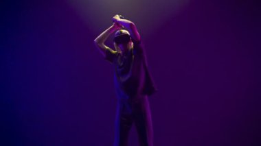 Energetic gamer playing virtual reality game using invisible sword. Pro man wearing VR headset playing online video game shooter with joysticks controllers as weapon. Cool retro neon colours room 