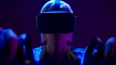 Energetic man using gaming controllers playing augmented reality simulation. VR headset youngster expressing interest engaged in futuristic metaverse world. Future innovation and technology concept