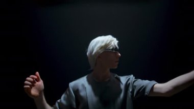 Gamer wearing virtual goggles in futuristic light. Focused man touching air in dark room. Blonde guy swiping interface immerse augmented reality in headset. Teenager enjoying trendy console simulation
