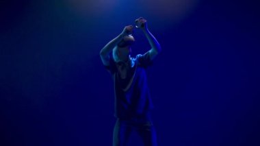 Blonde man playing virtual world game. Focused gamer holographic augmented reality glasses pretending draw bow enjoying in neon light. Guy VR digital space. Metaverse 3d modern technology concept