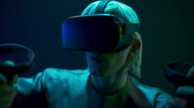 Excited man experiencing handheld trackpads videogame closeup. Impressed gamer using gadget for virtual reality on neon background. Futuristic goggles youngster playing. Future technology concept 
