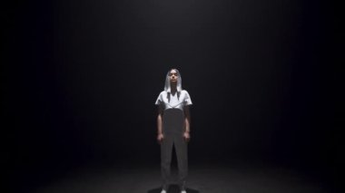 Gelecekçi kız karanlık odayı aydınlatacak. Gri elbiseli, gümüş saçlı güzel bir hippi. Siyah arka plana bakan çekici genç siber oyuncu. Şehir dansçısı genç yaşam tarzı 