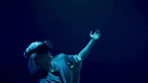 ネオンライトで踊る仮想現実プレーヤーが閉じます 暗室での精力的な男の経験回避シミュレーション ヘッドセットでゲームスイングを楽しむ未知の興奮ゲーマー 幸せなサイバー千年王国の男 — ストック動画