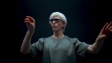 Yakın plan adam ışıkta metaevren simülasyonu oynuyor. Fütüristik milenyum, yüksek teknoloji gözlükleri ile güçlendirilmiş gerçeklik. Ciddi sarışın adam sanal arayüze dokunuyor. Gelecekteki siber yaşam tarzı.