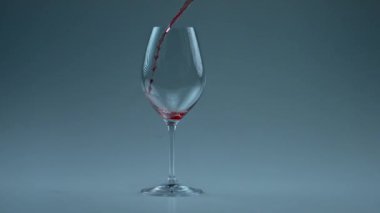 Şarap kadehinin içine ruhani bir sıvı sıçrıyor. Alkolik şaraplar temiz kadehe dökülüyor. Süper yavaş çekimde. Kırmızı içecek tazeleniyor, cam beyaz arka plan doluyor. Lüks zarafet tipple konsepti