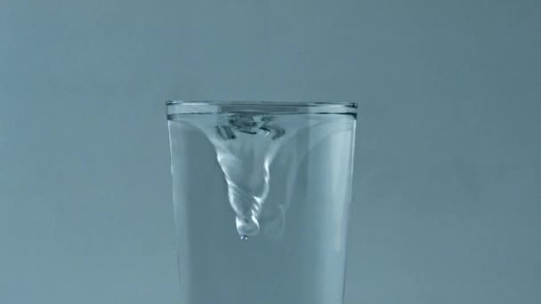 玻璃容器内的清澈冷水涡旋密闭 冰块在透明的玻璃杯中旋转 过滤过的水可以旋转 更新美味的饮料流淌慢动作 生态饮料 — 图库视频影像