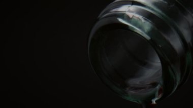 Süper yavaş çekimde kristal damlalarıyla yakın çekim boynu. Son su damlacıkları siyah arka planda cam şeffaf şişeden damlıyor. Susuzluk giderme konsepti için taze içecek.