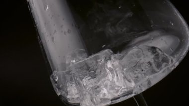 Siyah arka planda şeffaf boş şarap kadehinin içinde duran donmuş blokları temizleyin. Soğuk buz küpleri cam yüzeyde su damlalarıyla dolu temiz kadehlerle dolu. İçecek konseptini tazelemek.