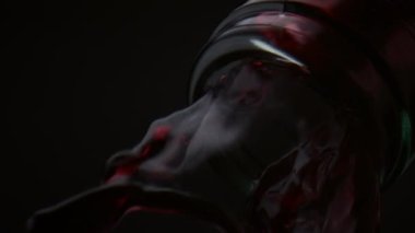 Şişe boyundan akan kırmızı şarap çok yavaş çekimde yakından geliyor. Siyah arka planda akan burgundy alkollü içecek. Gurme içecekler cam konteynırdan dökülüyor. Parti konsepti.