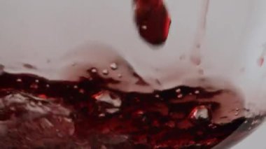 Beyaz arka planda şeffaf cam kadehin içine kırmızı şarap dökmek. Gurme gül alkolü, temiz şarap bardağına dökülüyor. Süper ağır çekimde lezzetli bir merlot sallıyor..