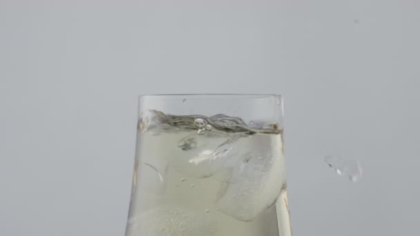 冰块漂浮在玻璃杯中 盛满了金酒 冷冰冰的香槟酒配上时髦的葡萄酒 冻结块下落透明杯在超级慢动作 更新酒水概念 — 图库视频影像