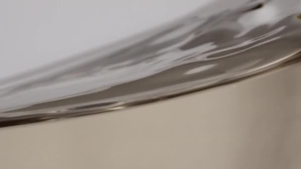 奢华的葡萄酒表面在超级慢动作宏观视野中旋转着玻璃杯 味道鲜美的葡萄饮料波特写 酒精饮料在透明的玻璃杯中旋转 旋转的金色液体质感 — 图库视频影像