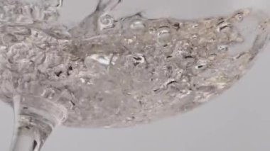 Altın şampanyası kristal şarap kadehinde fokurduyor. Alkol şarabı şeffaf kadehte köpüklü süper yavaş çekimde. Cam bardakta köpüren taze soda. Beyaz arkaplanda karbonatlı içecek