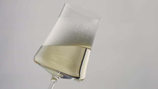迷人的香槟在优雅的玻璃杯中闪烁着灿烂的光芒 最后一滴酒以超慢的速度从酒体表面滑落 在时尚的葡萄酒白色背景中重新装饰饮料泡沫 奢侈的概念 — 图库视频影像