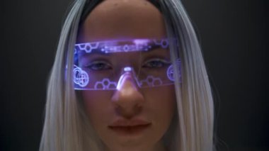 VR kulaklıklı kadın kamera görüntüsü veriyor. Modern video oyunları oynamaya hazırlanan yaratıcı kız. Görünmez ekran ile etkileşen akıllı gözlük kullanan gelecekçi genç yüz. Metaevren
