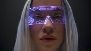 Gelecekçi VR gözlüklü genç yüz, yakın plan. Yaratıcı kadın kameraya bakıyor holografik artırılmış gerçeklik gözlüğü siyah arka planının keyfini çıkarıyor. Çevrimiçi video oyunu oynayan kız. Metaverse teknoloji konsepti
