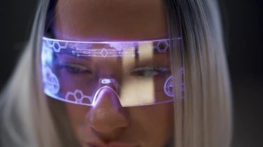 Odaklanmış bir kadın, VR kulaklığı izliyor. Siyah arka planda video oyunu oynayan sarışın oyuncu görünümlü gözlük. 3D filmden hoşlanan ilginç bir kız. Modern nano cihazlar, gelecekteki teknoloji konsepti 