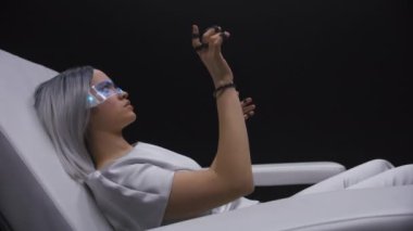 Kapanış kızı sensör eldivenleriyle arttırılmış gerçeklik oynar. Meta sarışın, görünmez nesnelere dokunuyor. Odaklanmış oyuncu ışıktaki konsol aygıtını kullanarak simülasyondan zevk alır. Gelecekteki siber uzay eğlencesi 