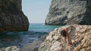 Rahat bir kadın kayalık Ursa plaj sabahında ayakta geriniyor. Sportif Afro-Amerikalı kız okyanus dalgaları yakınında yoga yapıyor. Formda sporcu kadın el kaldırıyor ve dışarıda egzersiz yapıyor..