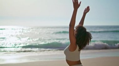 Sakin bir yogi kızı okyanus dalgalarının yanında durup Namaste elleri yapıyor. Afrika kökenli Amerikalı kadın güzel deniz kıyısında meditasyon yapıyor. Kıvırcık, ince, sporcu kadın dışarıda barış içinde yaşıyor..