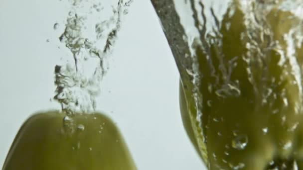 美味苹果溅液体特写 淡淡的背景中 淡淡的绿色的水桶滴下起泡的水 用新鲜的有机水果洗净维生素沙拉 健康成份反弹隔离 — 图库视频影像