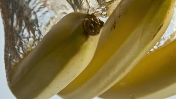 바나나는 배경에서 떨어진다 과일은 액체를 내놓습니다 아침에 맛있는 이국적 재료를 — 비디오