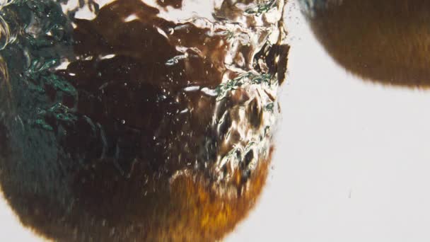 閉じたキウイは泡の中で水をはねます 甘いトロピカルフルーツは 軽い背景で液体洗浄をドロップします 夏のデトックス料理のためのおいしい有機製品 健康的なライフスタイル ビーガン栄養コンセプト — ストック動画