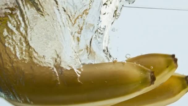 有機バナナの落下水を閉じます 透明な泡状の液体に浮かぶおいしいトロピカルフルーツ 天然エキゾチックな成分が表面を上昇 甘い朝食のコンセプトのための健康的な料理 — ストック動画