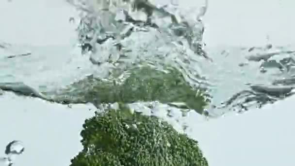 有機ブロッコリースプラッシュ水を閉じます フィットネス野菜の透明なガラス容器落下 熟した緑の成分は軽い背景を洗うバウンス ベジタリアンデトックス栄養 フード コマーシャル ショット — ストック動画