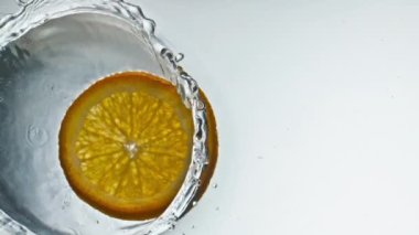 Lezzetli portakal dilimleri pürüzsüz su sıçratıyor. Taze tropikal meyve parçaları ışık arka planında şeffaf sıvı düşüyor. Lezzetli yaz partisi kokteyli pişiriyorum. Vitamin beslenme kavramı.