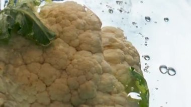 Yakın plan karnabahar baş suyu hafif arka planda yüzer. Taze organik sebze kaynayan sıvının içinde sıçrıyor. Vejetaryen fitness besin malzemesi pişiriyorum. Doğal ürün mutfak sanatı konsepti.