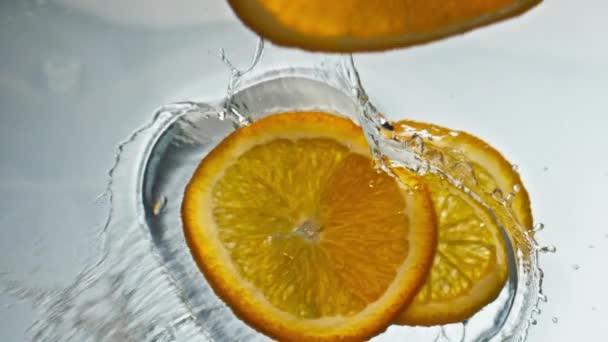 오렌지 조각을 클로즈업해서 액체를 튀기는 칵테일을 배경으로 만들었습니다 음료를 떨어뜨리는 — 비디오