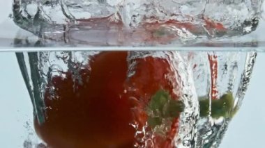 Tatlı biberli su sıçratıyor. Kırmızı mevsimlik sebze, şeffaf sıvı düşerek kabarcıklar oluşturur. Sağlıklı salata arkaplanı için taze organik malzeme. Fitness yaşam tarzı konsepti.