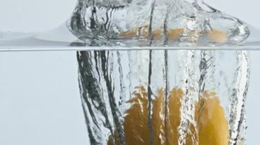 Hafif arka planda limon sıçrama sıvısı. Taze tropikal narenciye, şeffaf suda hava kabarcıkları oluşturur. Güzel bir ekşi sarı meyve reklamı. Yaz vitamin kokteyli konsepti.