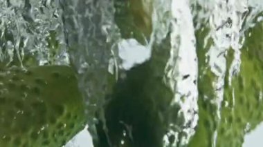 Organik salatalıklar baloncuklara su sıçratır. Sağlıklı yaşam tarzının güzel bir yemek reklamı. Şeffaf sıvı içinde akan taze yaz sebzeleri. Çiğ düşük kalorili yiyecekler.