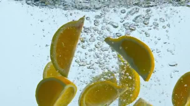 Taze Portakal Dilimlerini Temiz Sıvıya Döküyorlar Parlak Turunçgiller Kabarcıklarla Yüzeyine — Stok video