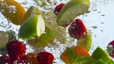 Yakın plan meyve parçaları beyaz arka planda temiz su suları. Ağır çekimde baloncuklarla yüzen portakal aromalı nane şekeri. Sağlıklı beslenme için lezzetli vitamin gıdaları.