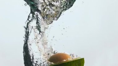 Sarı tohumu olan yarı yeşil avokado süper yavaş çekimde suyun altına düşüyor. Lezzetli, olgun sebzeler su altında kabarcıklar yapıyor. Sağlıklı yaşam tarzı için vitaminli organik sebze.