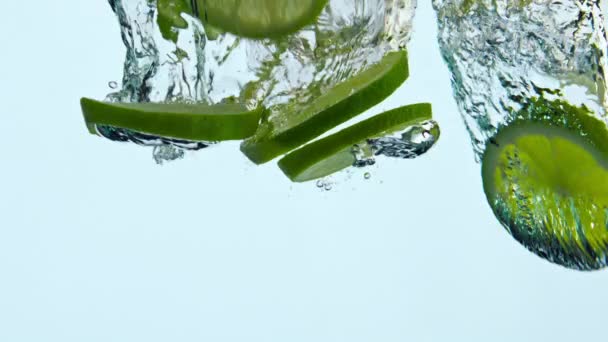 多汁的绿石灰落在水晶球上 使气泡在白色的背景上飞溅 切片酸新鲜柑橘漂浮在水下的超慢动作特写 为健康的生活方式更新水果饮料 — 图库视频影像