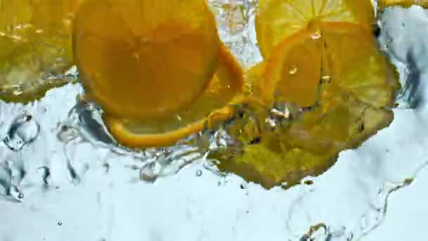 Pièces Lumineuses Oranges Éclaboussant Liquide Transparent Sur Fond Blanc Fermer — Video