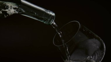 Büyüleyici bir manzara, şişeden temiz bardağa altın şarap dökme görüntüsü, yakın plan. Akım sarı alkol içeceği süper yavaş çekimde şarap bardağına akıyor. Gurme içecek konsepti.