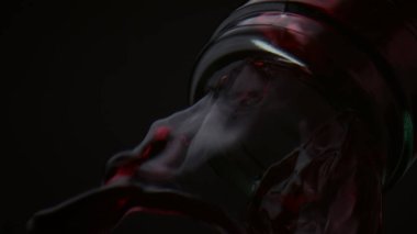 Şişe boyundan akan kırmızı şarap çok yavaş çekimde yakından geliyor. Siyah arka planda akan burgundy alkollü içecek. Gurme içecekler cam konteynırdan dökülüyor. Parti konsepti.