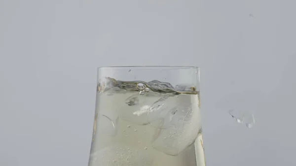 黄金のワインの完全な氷のキューブ浮動ガラスのゴブレットを閉じます スタイリッシュなワイングラスで冷たい輝くシャンパンは素晴らしいです 凍結ブロック超スローモーションで透明なカップを落下 飲み物のコンセプト — ストック写真