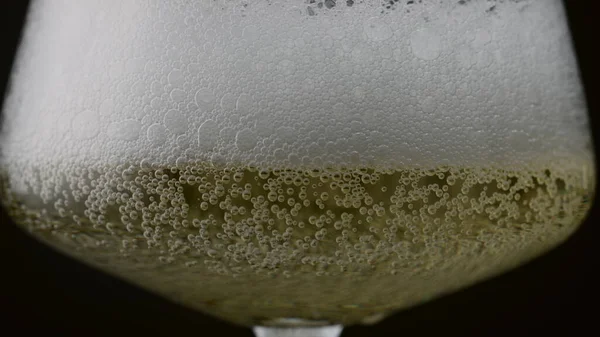 黒の背景に金色の液体の表面上に上昇白い輝くワイン泡泡を閉じます 透明なワイングラスの中のおいしいシャンパンのシズル 超スローモーションで破裂する気泡 — ストック写真